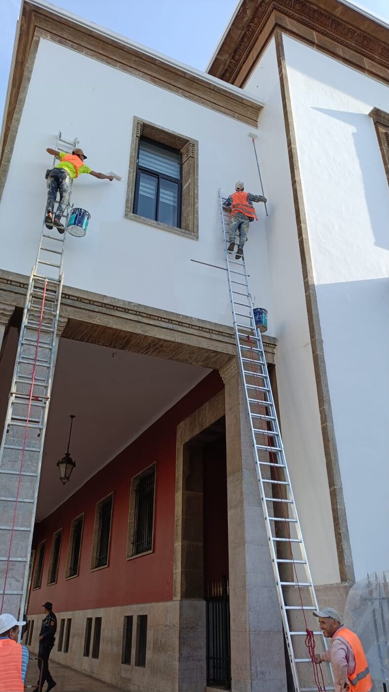 Deux peintres sur échelles repeignant une façade blanche