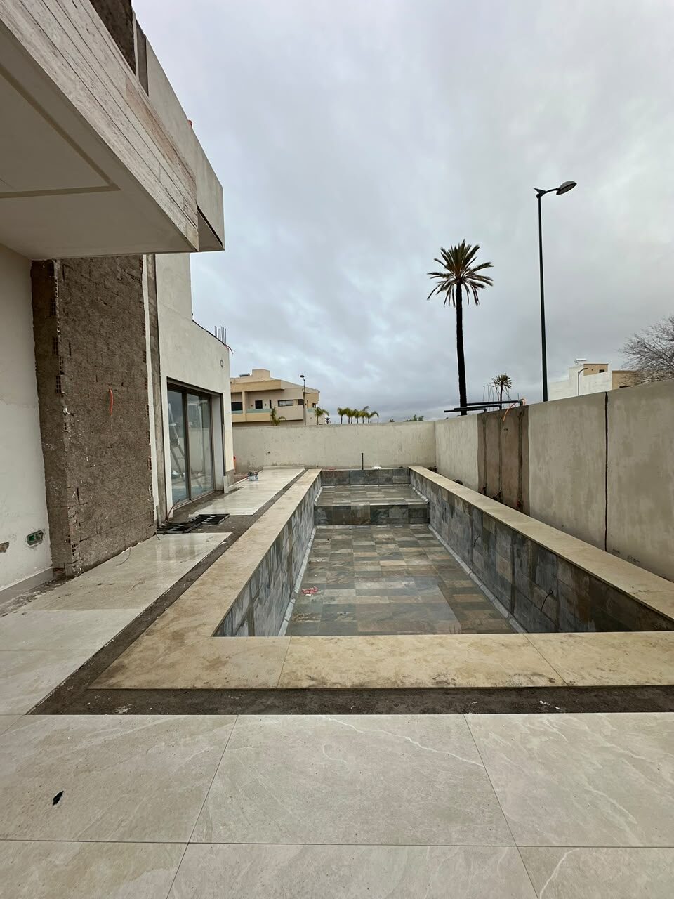 Piscine carrelée et terrasse en pierre claire
